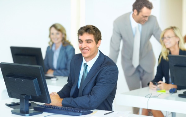 Smiling business man sitting at his computer desk